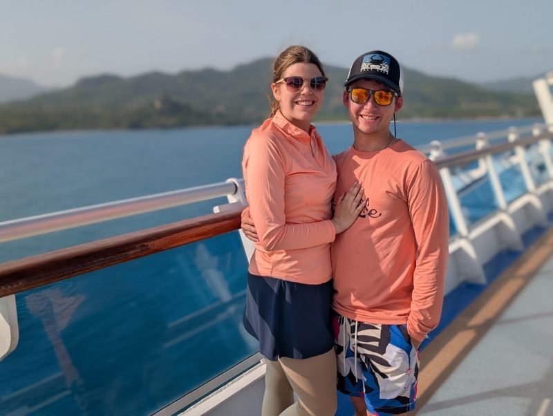 Smiling together at a ship's rail in matching coral shirts.