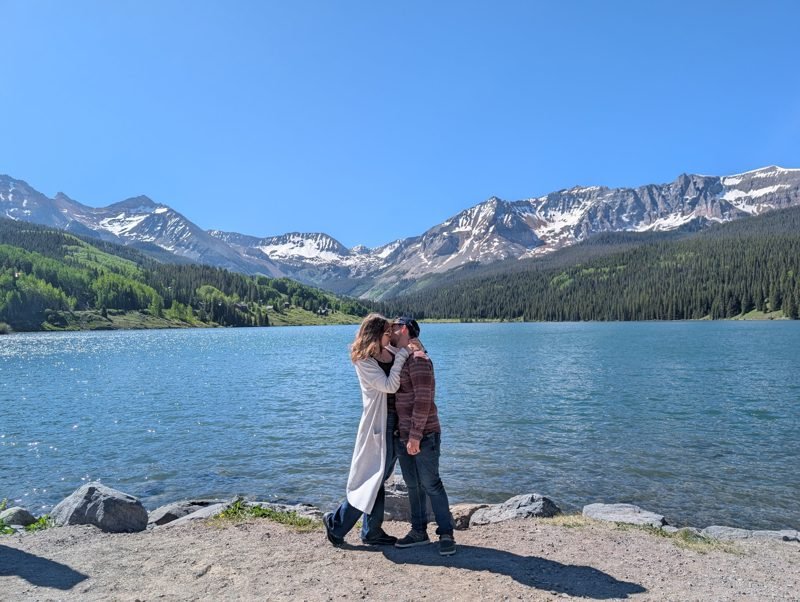 Kissing at the edge of a mountain lake.