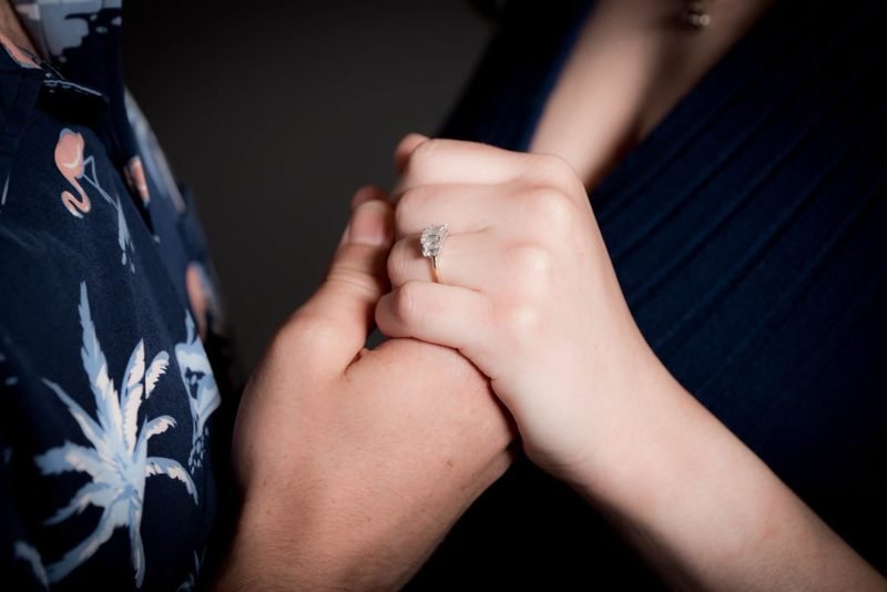 Close-up of their held hands and the engagement ring.