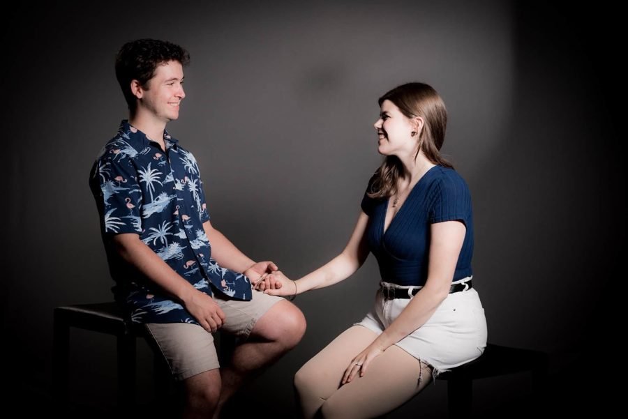 Seated face to face, holding hands, in a studio.