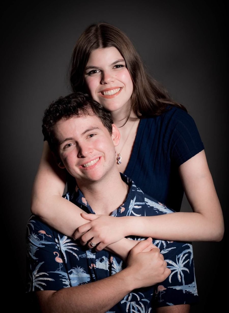 Margaret with her arms around her fiancé's shoulders, both smiling at the camera.