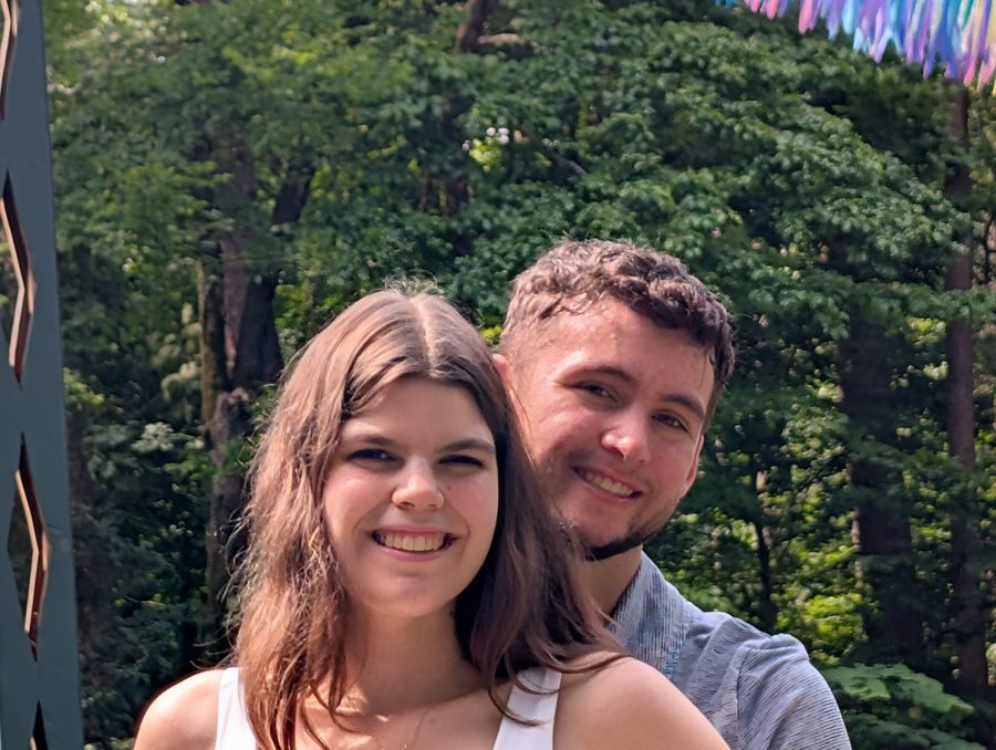 Close portrait of the couple smiling under summer trees.